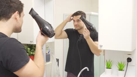 The-man-drying-his-hair-with-a-blow-dryer.